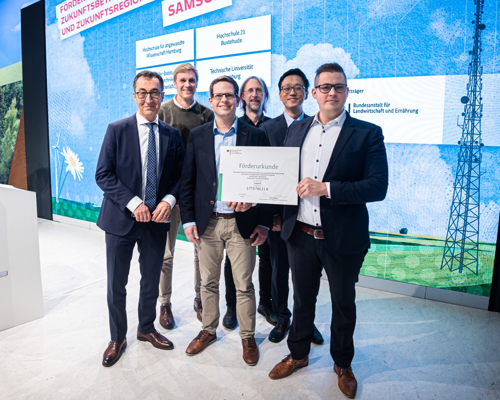 Start des Obstbau-Digitalisierungsprojekts »SAMSON«: Bundesminister Cem Özdemir überreicht den Förderbescheid an Alexander Kammann (hochschule 21), Christian Böhlmann (Fraunhofer IFAM), Prof. Dr. Tim Tiedemann (HAW Hamburg), Jiahua Wei (TU Hamburg) und Benjamin Schulze (Fraunhofer IFAM); (v.l.n.r.; © BMEL/photothek).